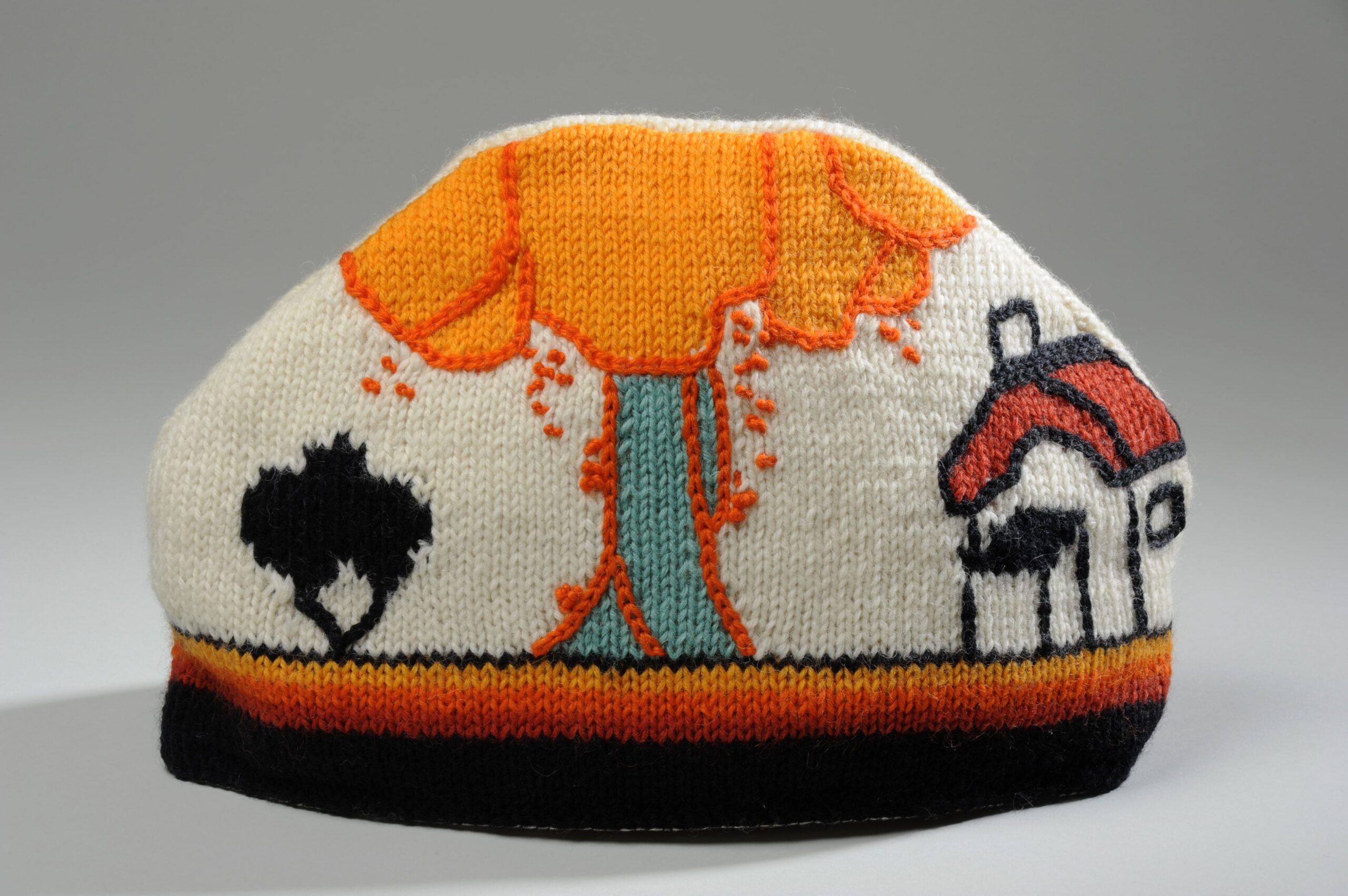 Tea cosy with a tree, bush and house in Clarence Cliff style
