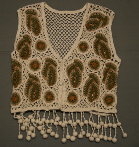 Crochet waistcoat with tassels around bottom, each of which has a chain of crocheted balls, and brown with dark green leaf mobifs.