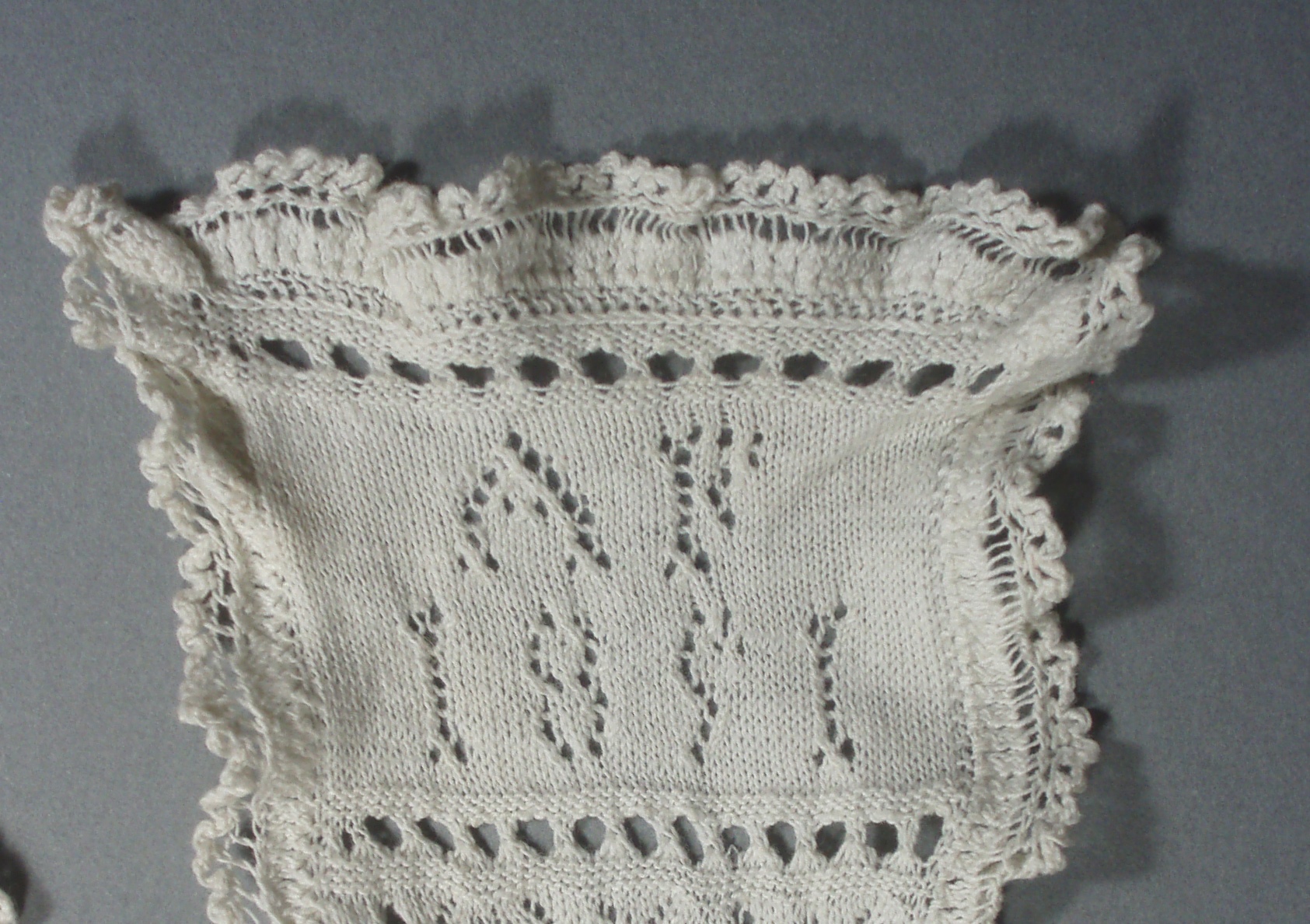 Detail showing the initials AF and the year 1891 knit into the sampler with openwork stitches.