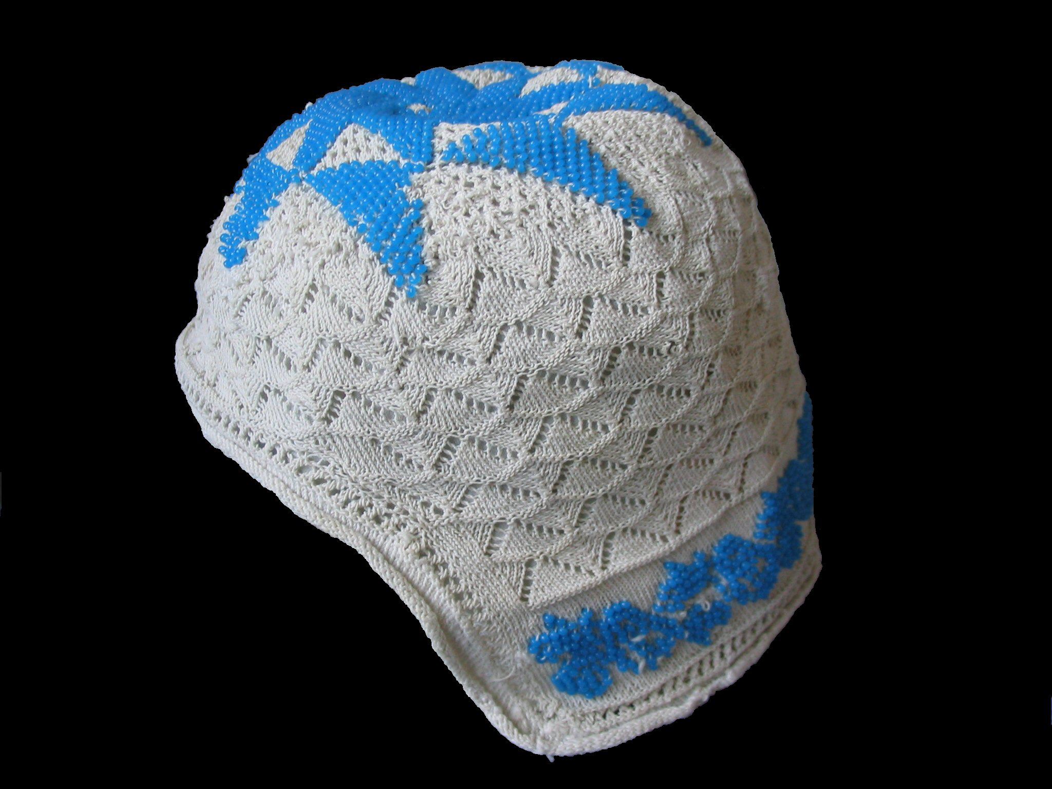 Childs bonnet, knit with openwork triangles and triangle designs in blue beads at the top and across the back of the neck.