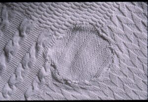 Visible repair to a damaged section of knitted bedspread