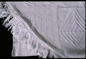 Fringd and triangular knitted panel at the edge of a bedspread