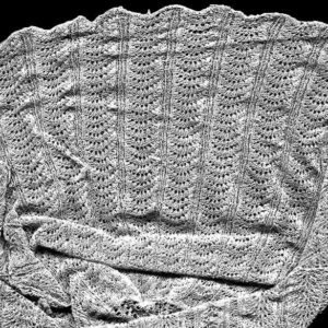 Close up of knitted cap showing openwork fans arranged in columns up the cap.