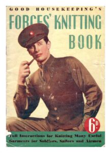Cover of Good housekeeping's Forces' Knitting Book showing young mad wearing military style cap, shirt and trousers and a knit sleeveless cardigan in plain stocking stitch with moss stitch borders - and smoking a pipe