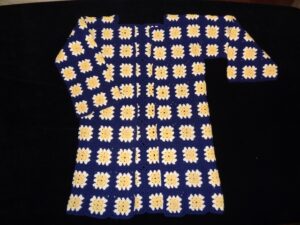 Coat made from crochet granny squares: dark blue grid with white and yellow centres to the squares
