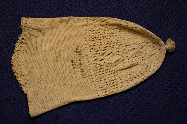 Knitted bed hat with open work top and borer and Captain Tweedie 1826 embroidered on it