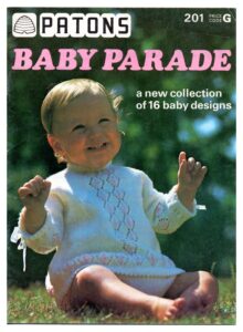 Cover of Patons Baby Parade (201) with baby wearing sweater with columns of open- and colour-work diamonds up the front and a row of similar diamonds round the cuffs and bottom