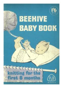 Cover of Beehive Baby Book showeing baby lying on chshion loding yarn to be wound onto ball.