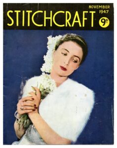 Cover of Stitchcraft November 1947. Lady in fluffy white bolero holding a white posy.