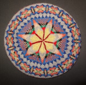 Tam with central star and bright red, yellow, orange, green, blue, brown and cream pattern.