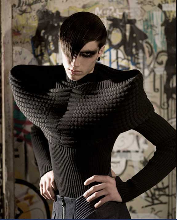 Male model wearing black knitted top with dramatic shoulders.
