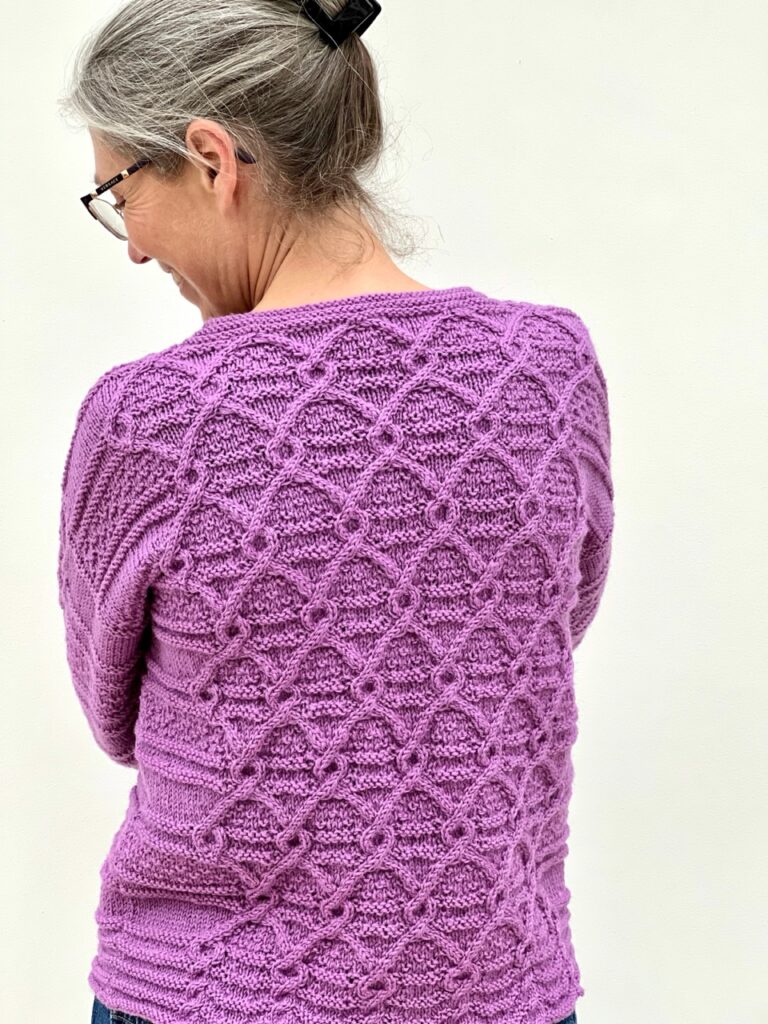 Emma Vining wearing a purple cabled sweater of her own design