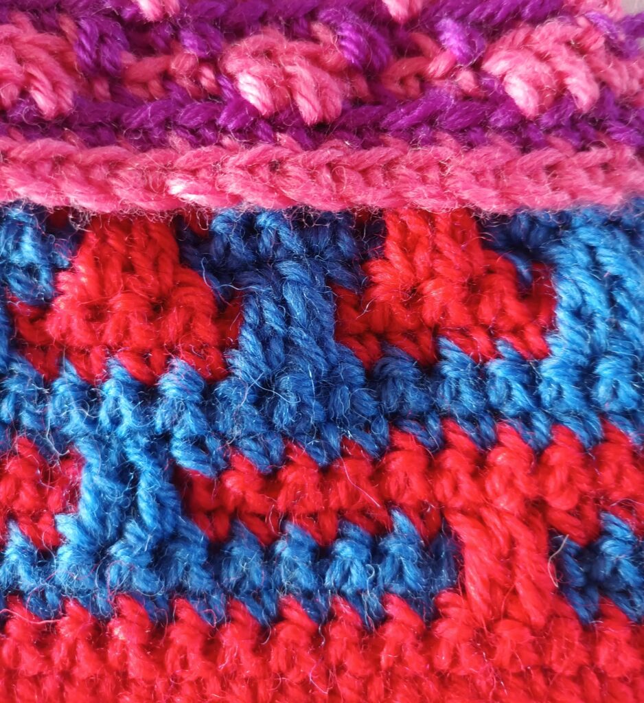 Photograph of section of mosaic crochet in blue, red, pink and purple