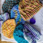 Collection of seven crochet hats in a variety of colours.