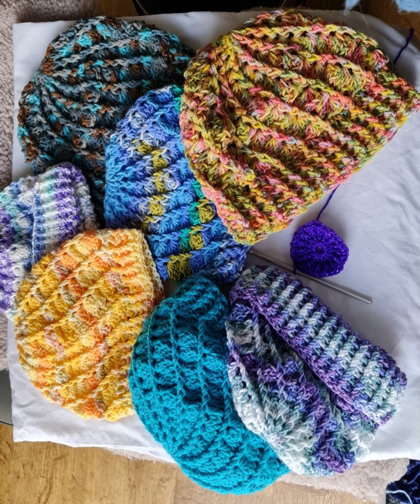Collection of seven crochet hats in a variety of colours.