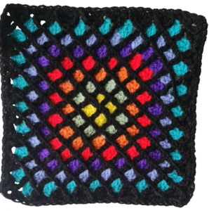 Photograph of lattice crochet with a black lattice and brightly coloured squares within it reminiscent of stained glass.