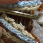 Scissors cutting a steek that has been reinforced using crochet