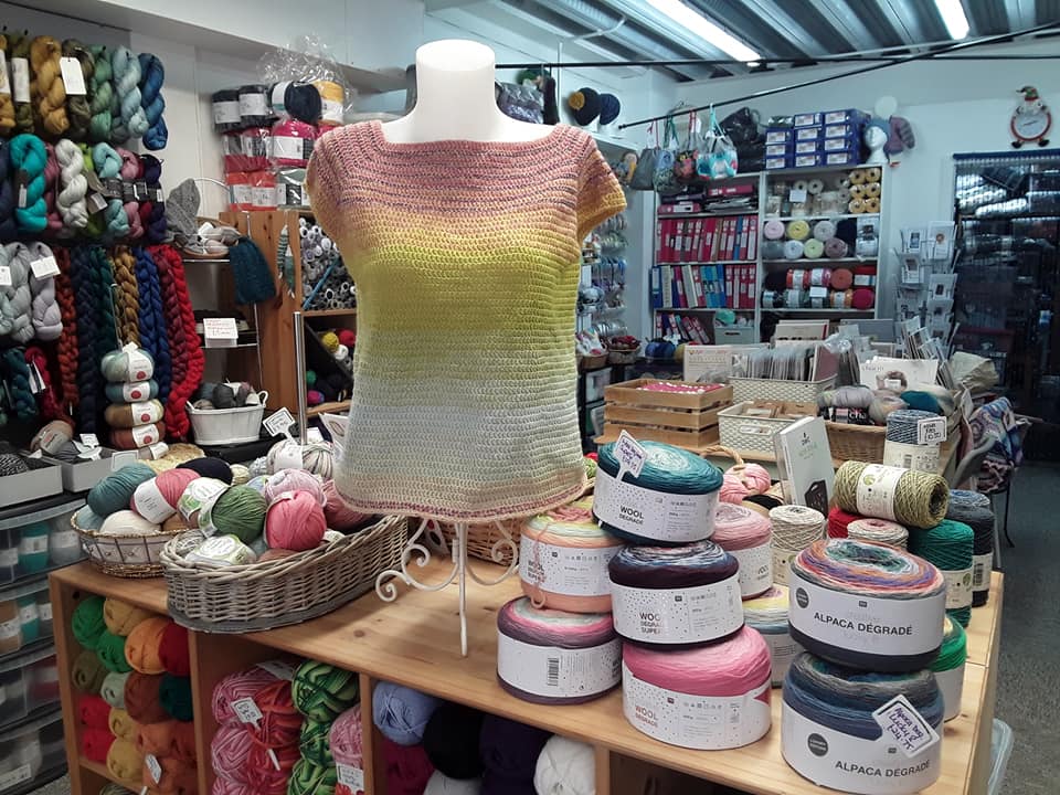 Interior of Pins & Needles (Devizes) featuring knitted short sleeved top on a stand and a wide selection of yarns