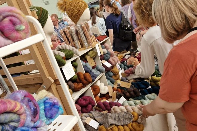Customers handling skeins of yarn on a stall