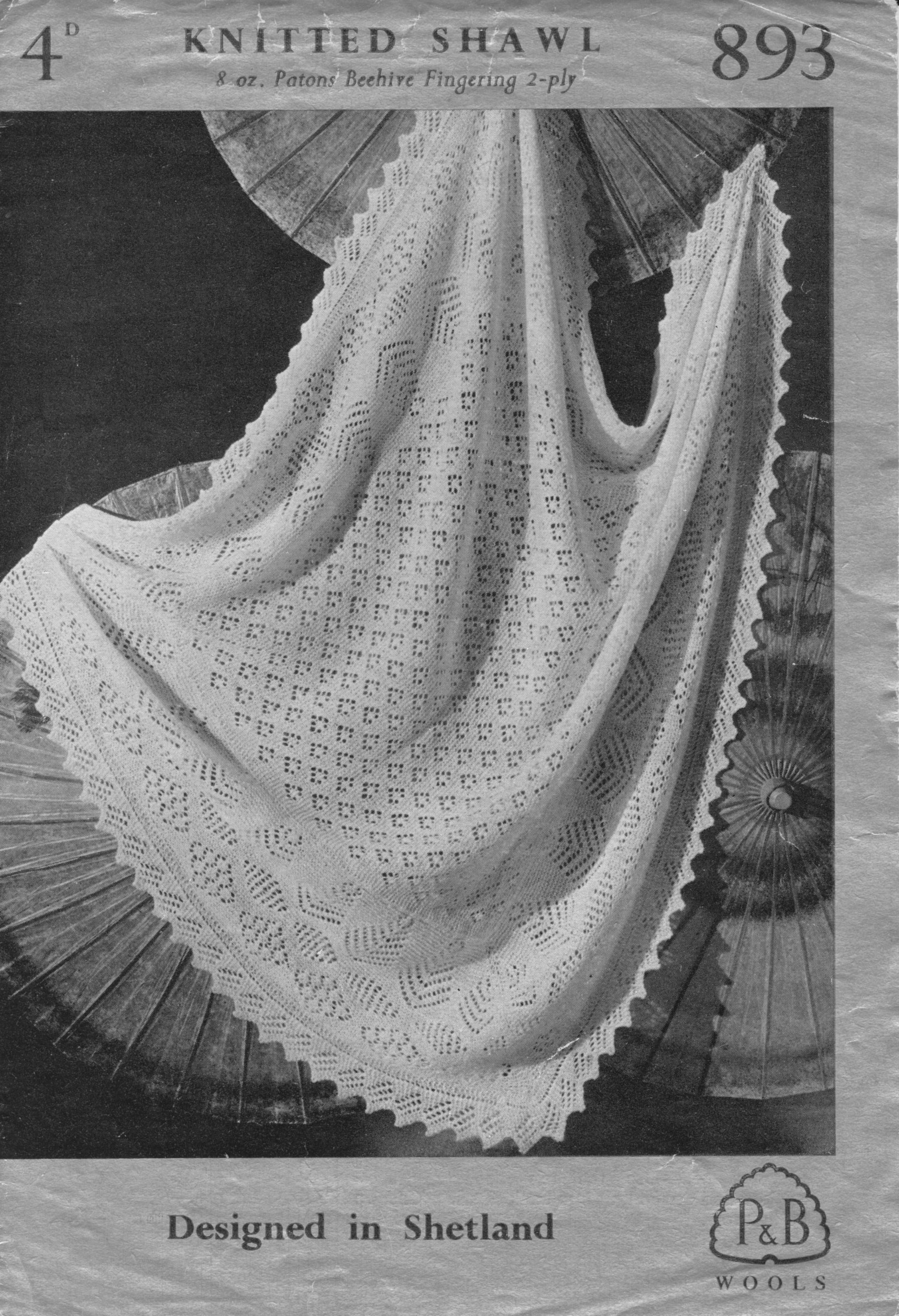 Square knitted lace shawl with saw tooth border. Displayed draped across parasols.