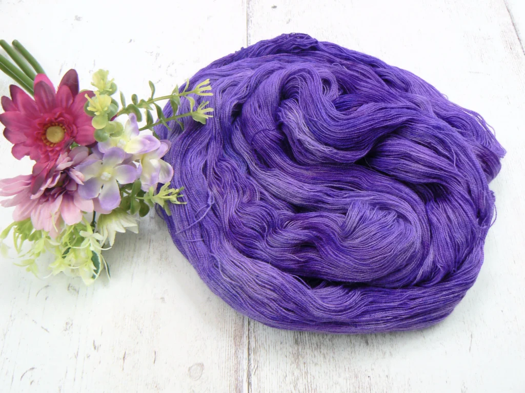 Purple yarn next to a posie of flowers