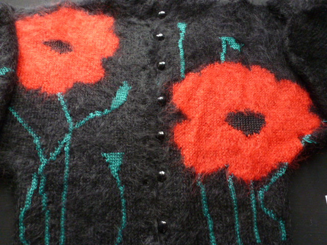 Close-up of poppy motif in knitted mohair jumper.
