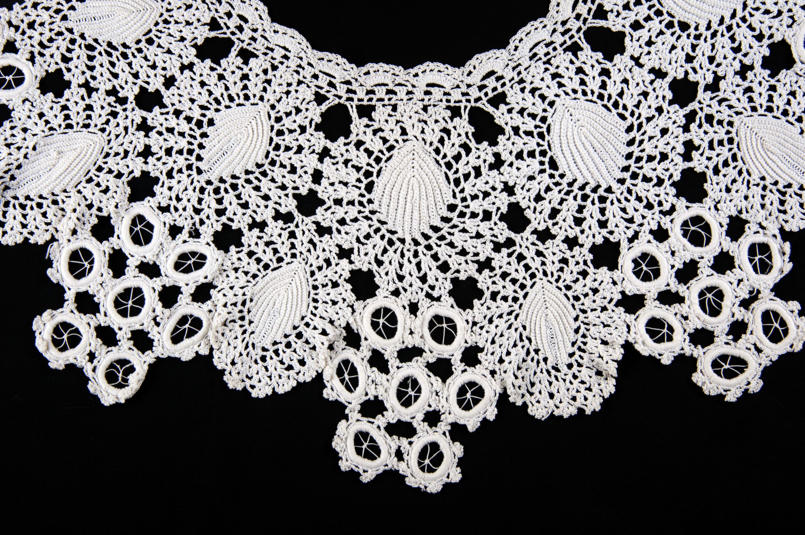 Detail of white crochet collar with design based on circles and leaves