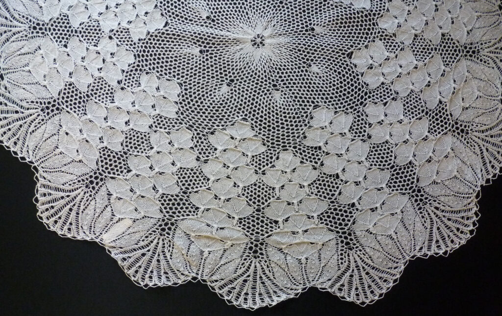Detail from knitted lace tablecloth using a foxglove pattern radiating from the centre.