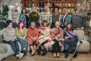 Contestants, judges and Tom Daley sitting on the Game of Wool sofas. Back row-Holger, Dipti, Ailsa, Simon, Isaac, Stephanie and Gordon Front row- Lydia, Meadow, Di, Tom, Sheila and Tracy